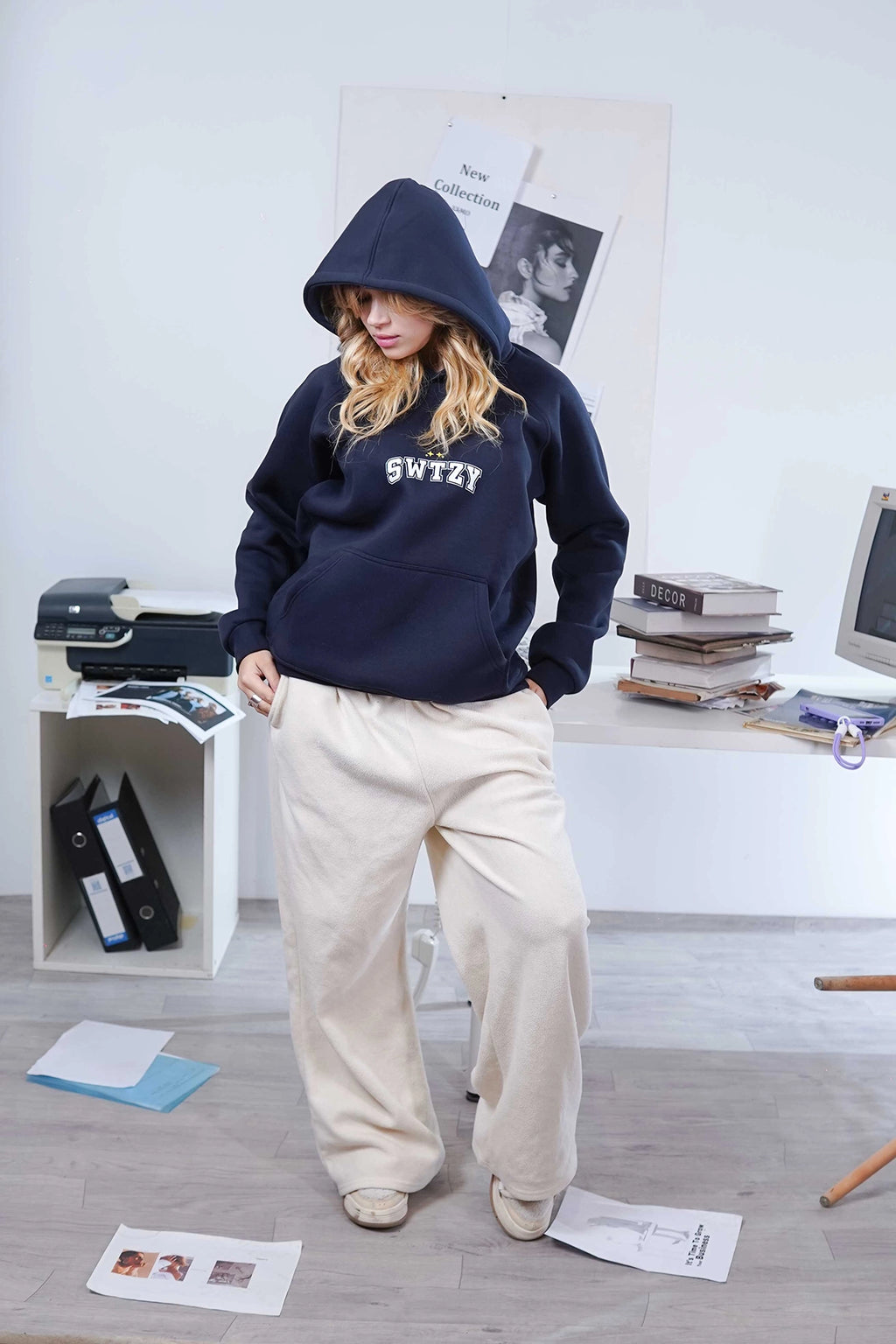 Person wearing a navy hoodie with 'SWTZY' text in a casual indoor setting.